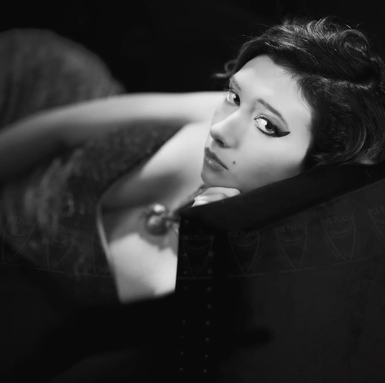 Model lying down on sofa and looking at camera. Black and white image.