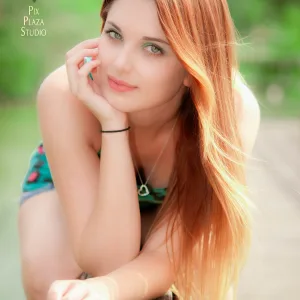 Ginger hair girl outdoors sitting on fence and leaning forward