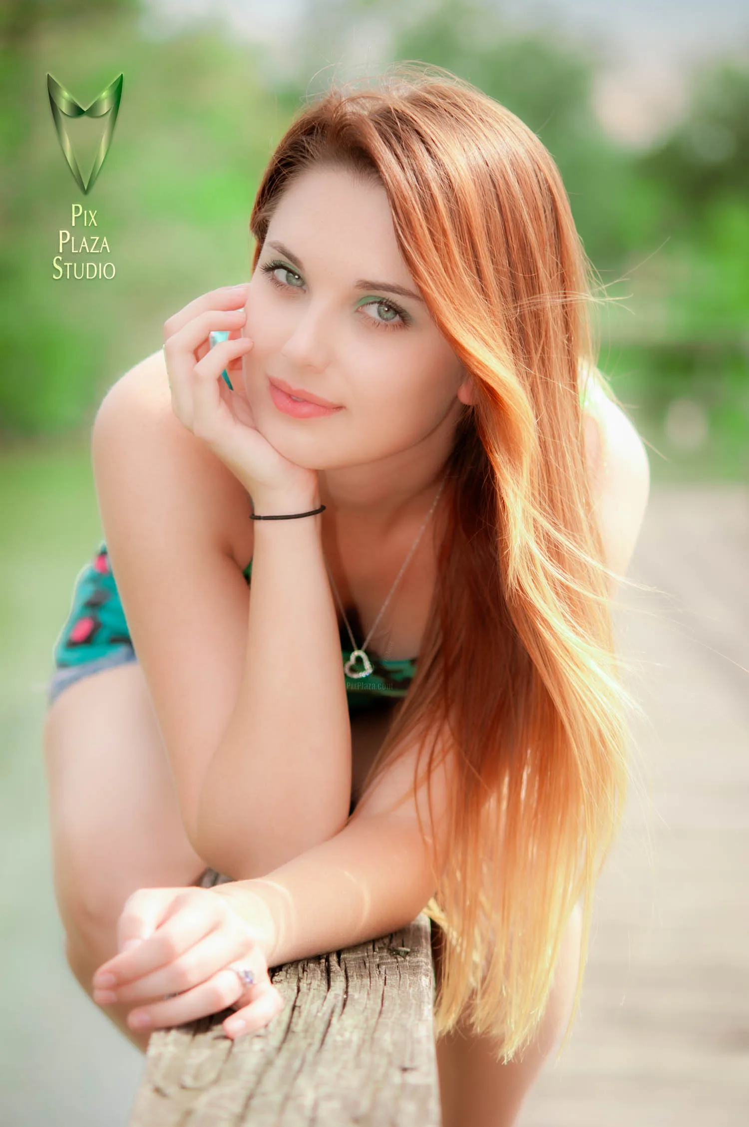 Ginger hair girl outdoors sitting on fence and leaning forward